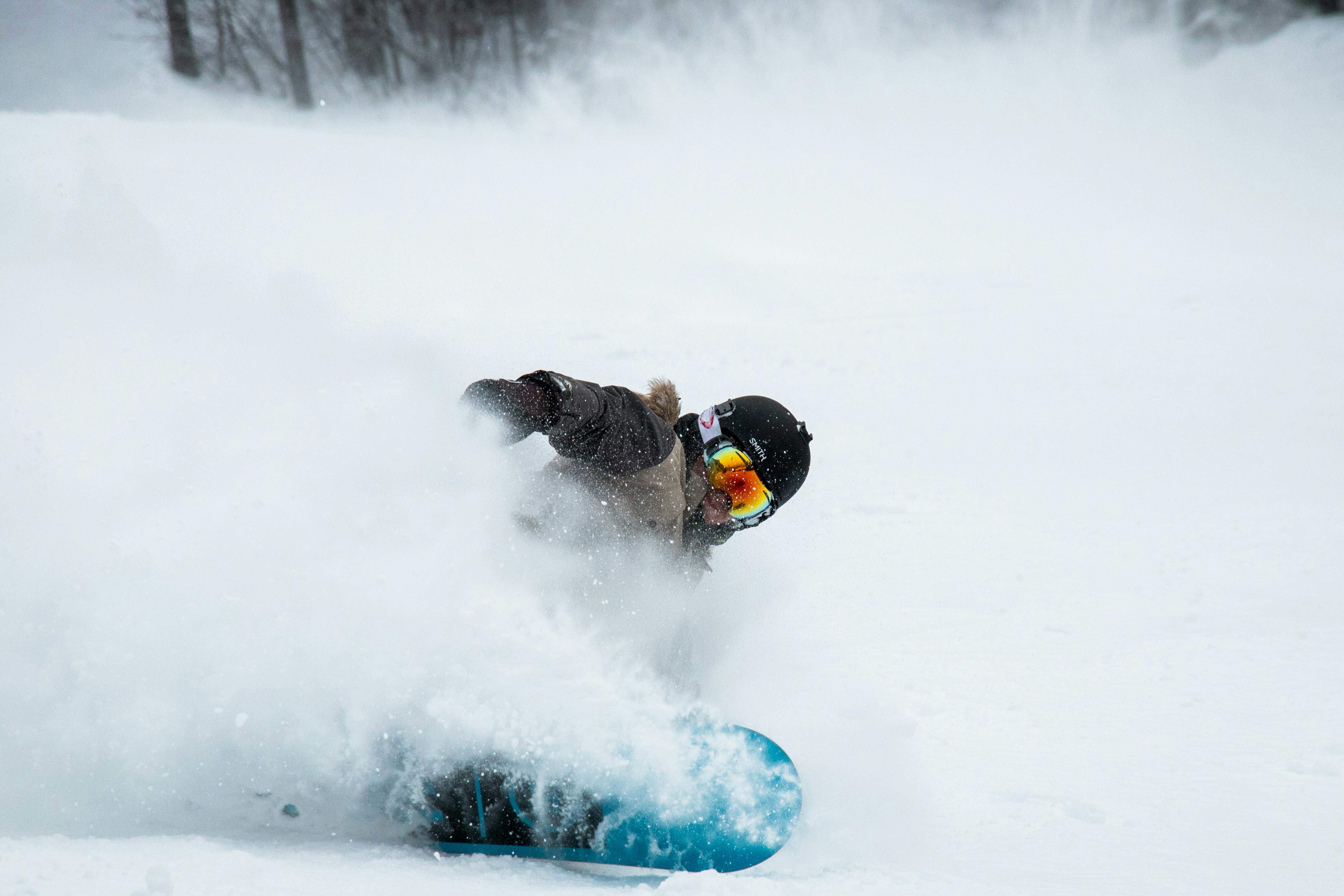 A snowboarder turns through deep powder.