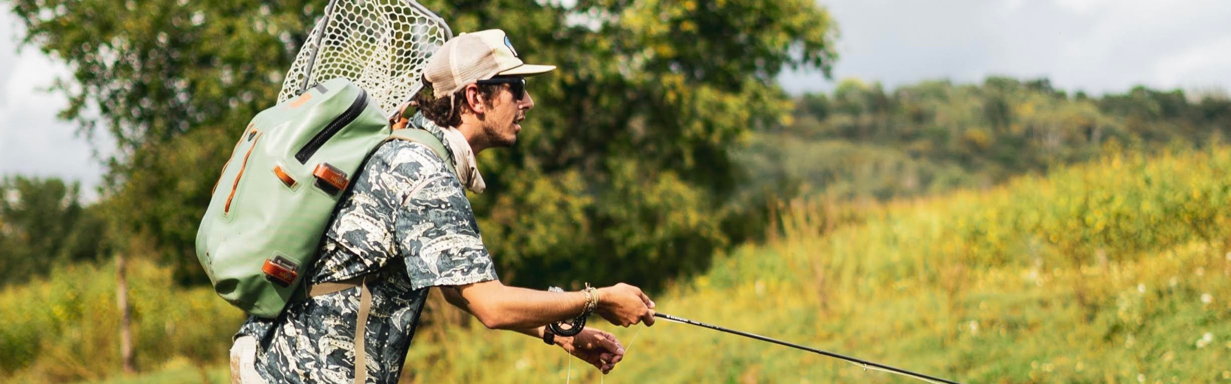 A man fly fishes while wearing a pack. 