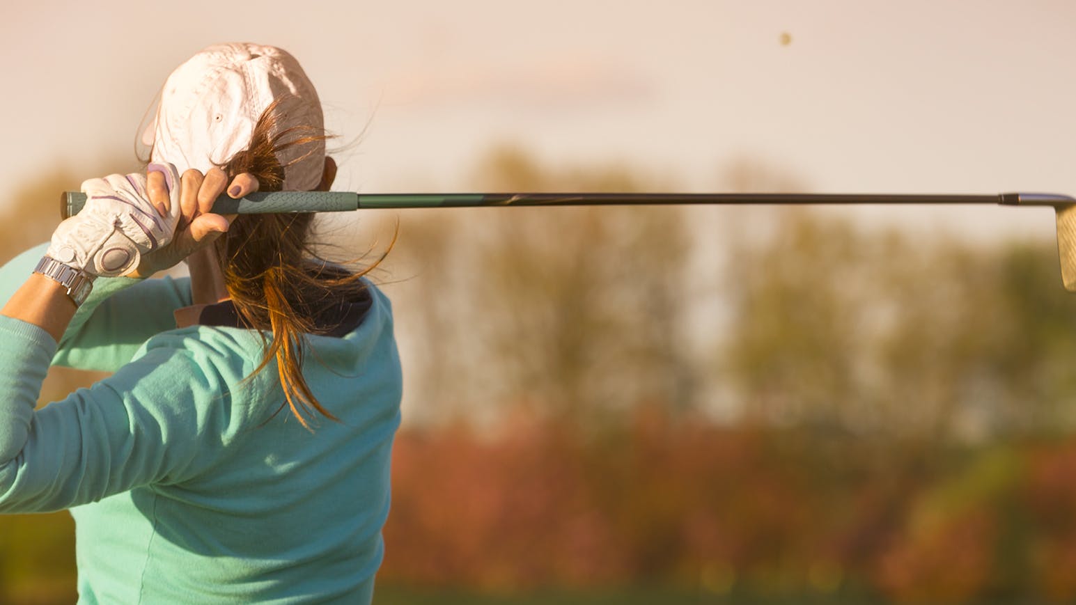 A woman swings a golf club. 