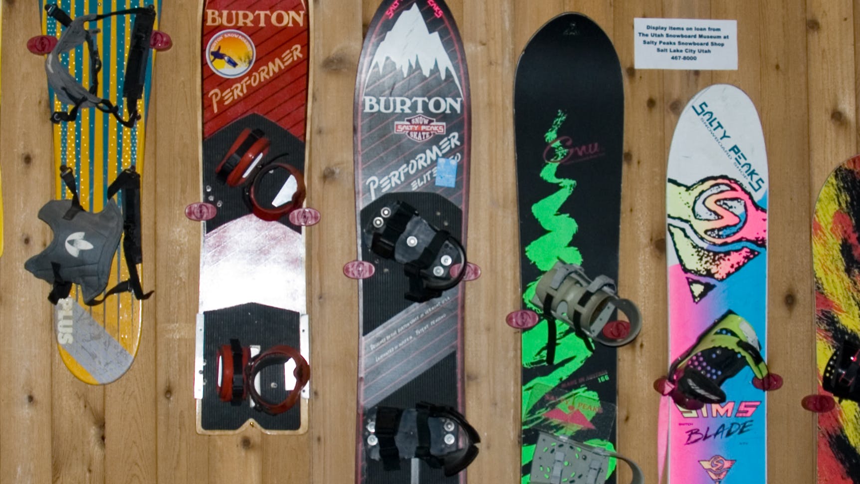 Several generations of snowboards hanging on a wall. 