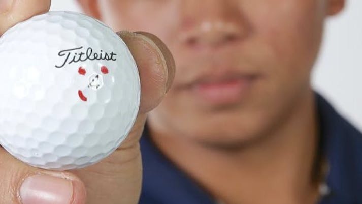 A man holding a Titleist Pro V1 Golf Ball. 