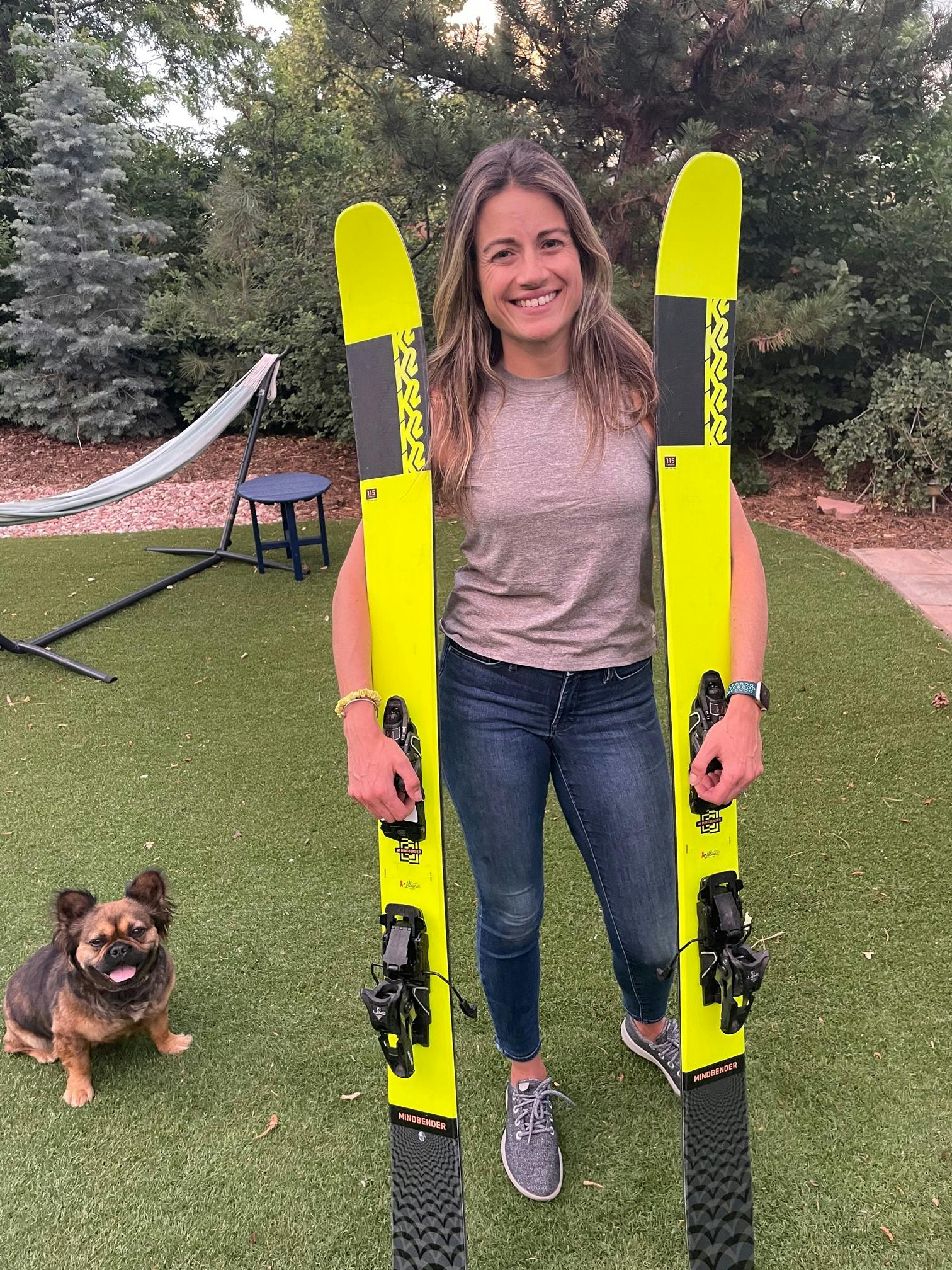 A woman holds the K2 Mindbender 116C skis.