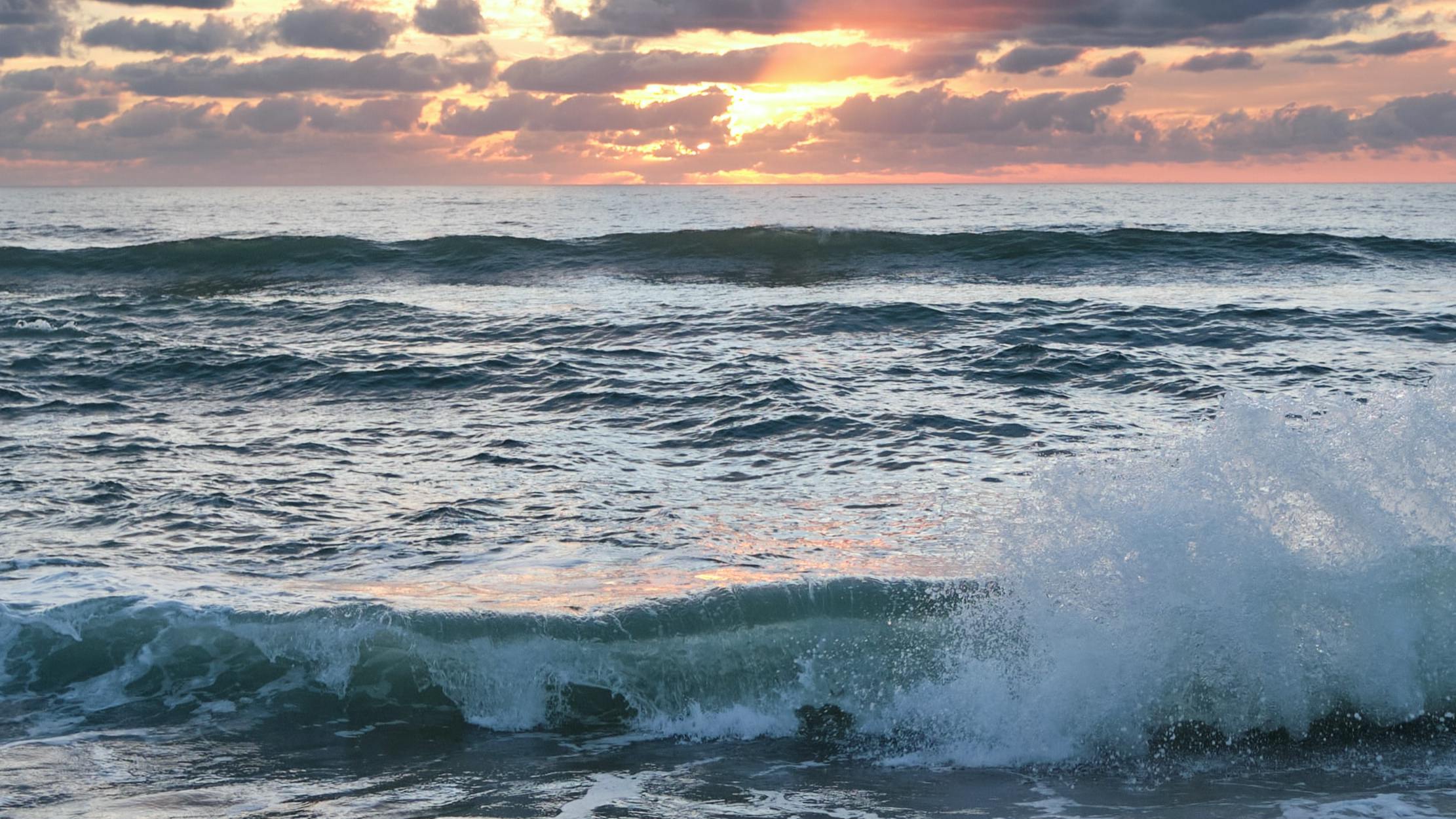 Waves crash at sunset or sunrise.