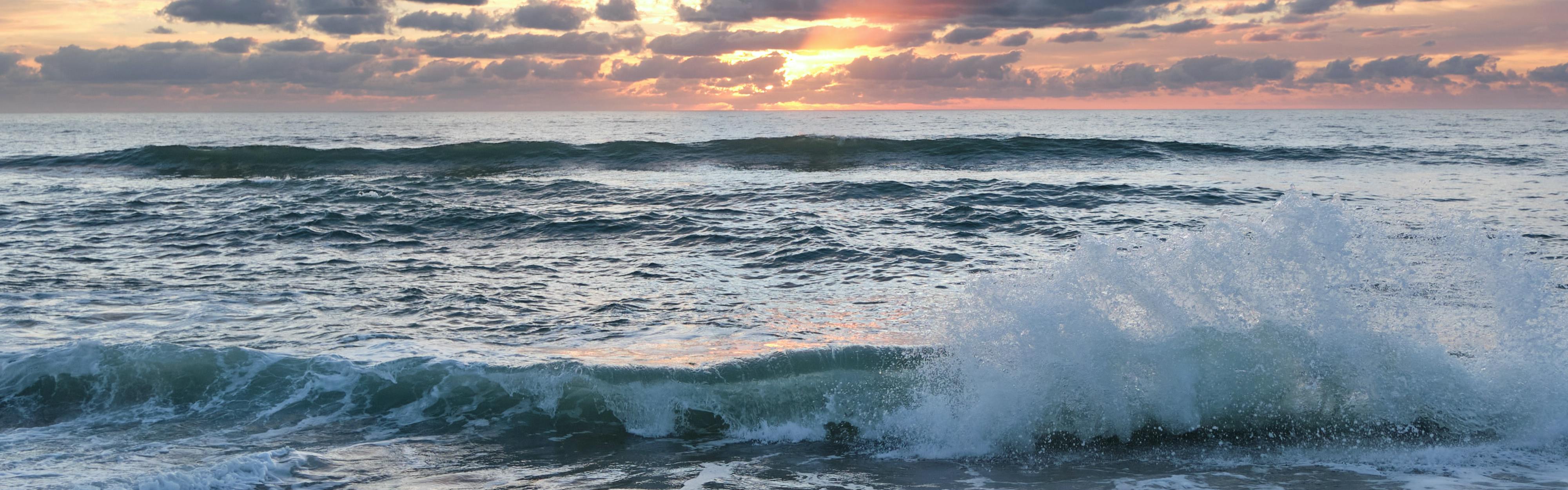 Waves crash at sunset or sunrise.