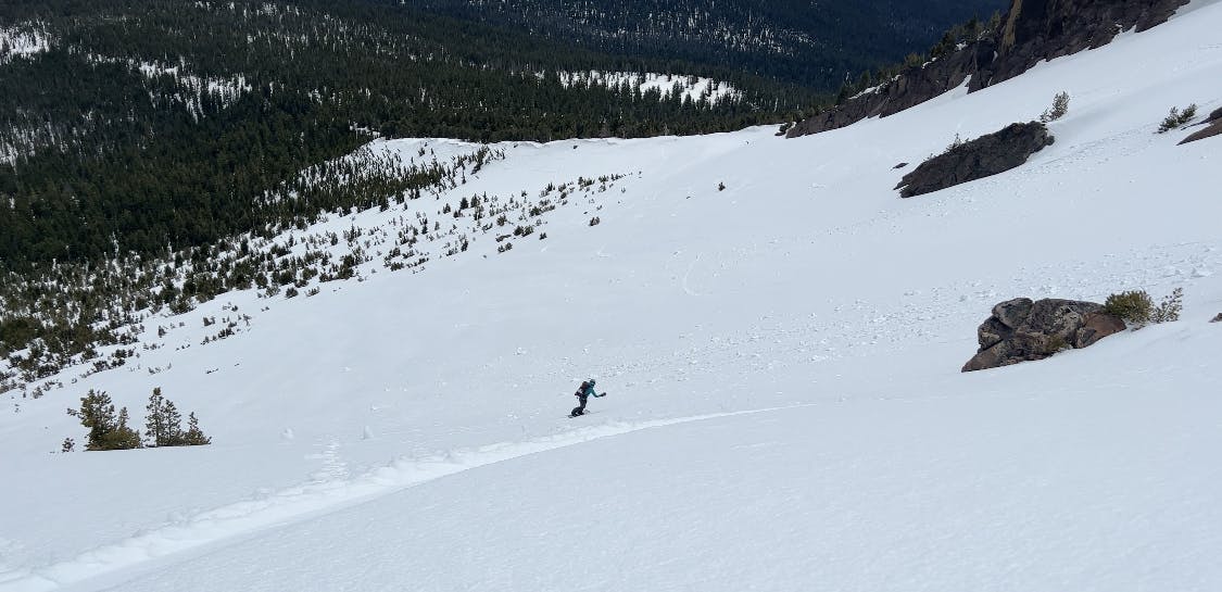 A snowboarder turning down a snowy mountain. 