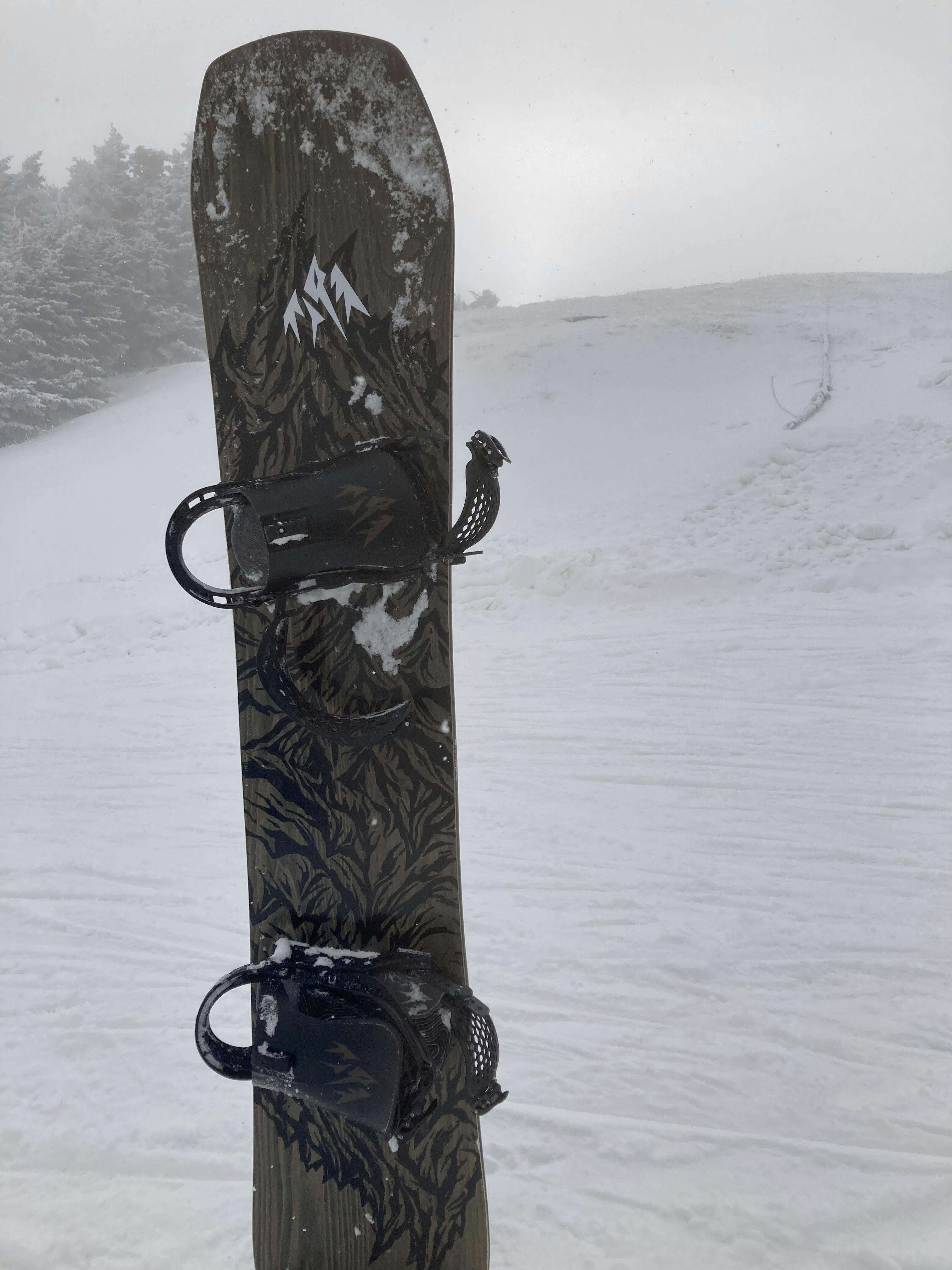 A snowboard sticking in the snow. 