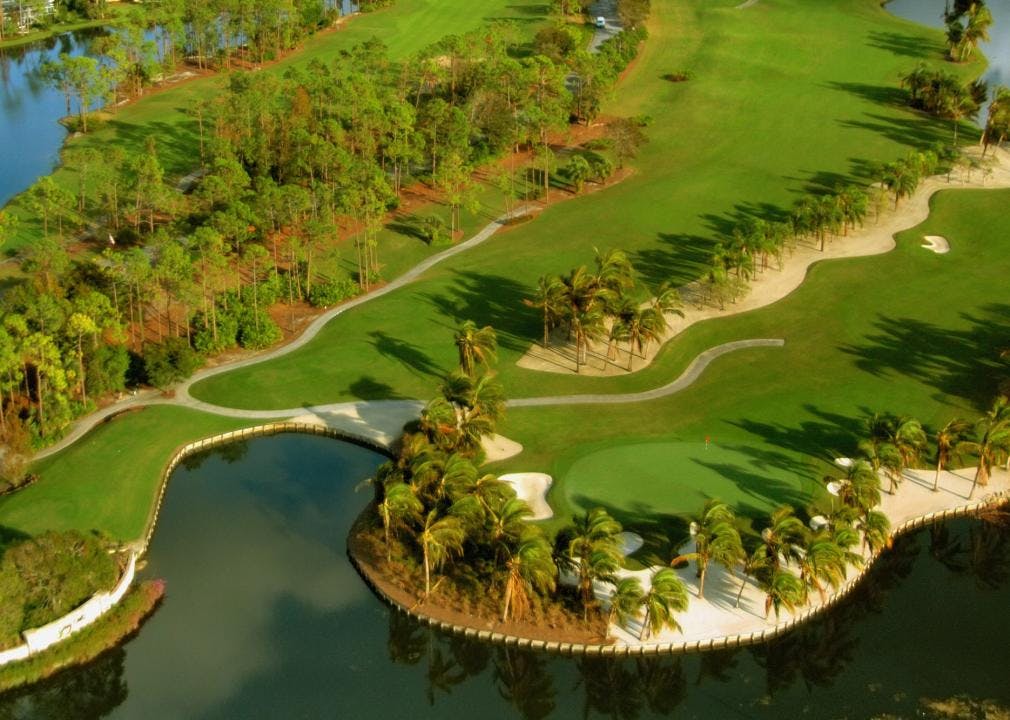 Aerial view of a golf course lined with palm trees and bounded by a lake