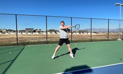 A tennis player hitting a tennis ball with the Wilson Pro Staff 97 V13.0 Racquet · Unstrung.