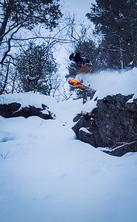 A snowboarder riding off a cliff. 