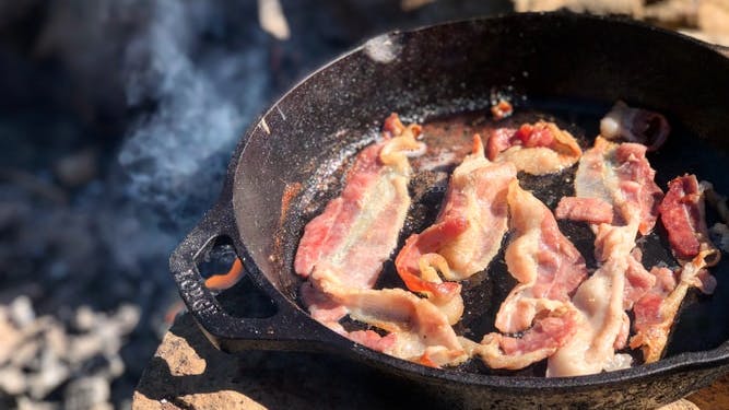 Bacon cooks in a cast iron skillet