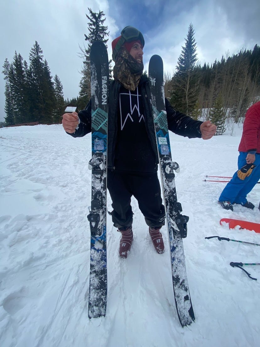 A skier stands with his skis and boots. 