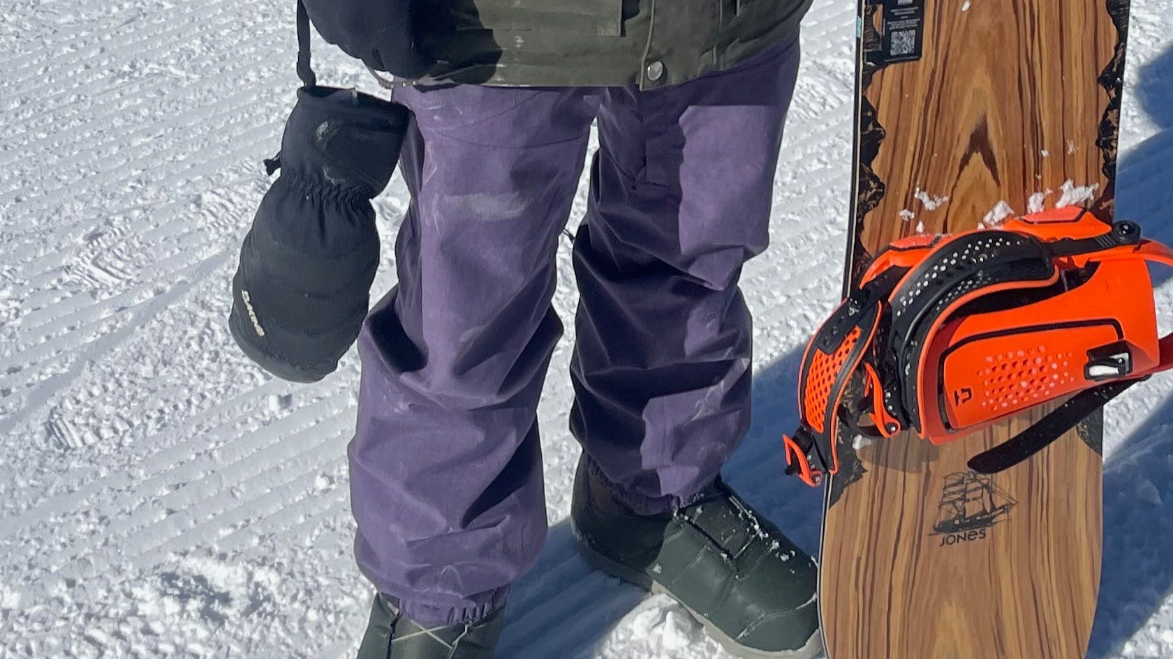 A snowboarder standing in his Burton Men's Cargo Pants, holding a snowboard. 