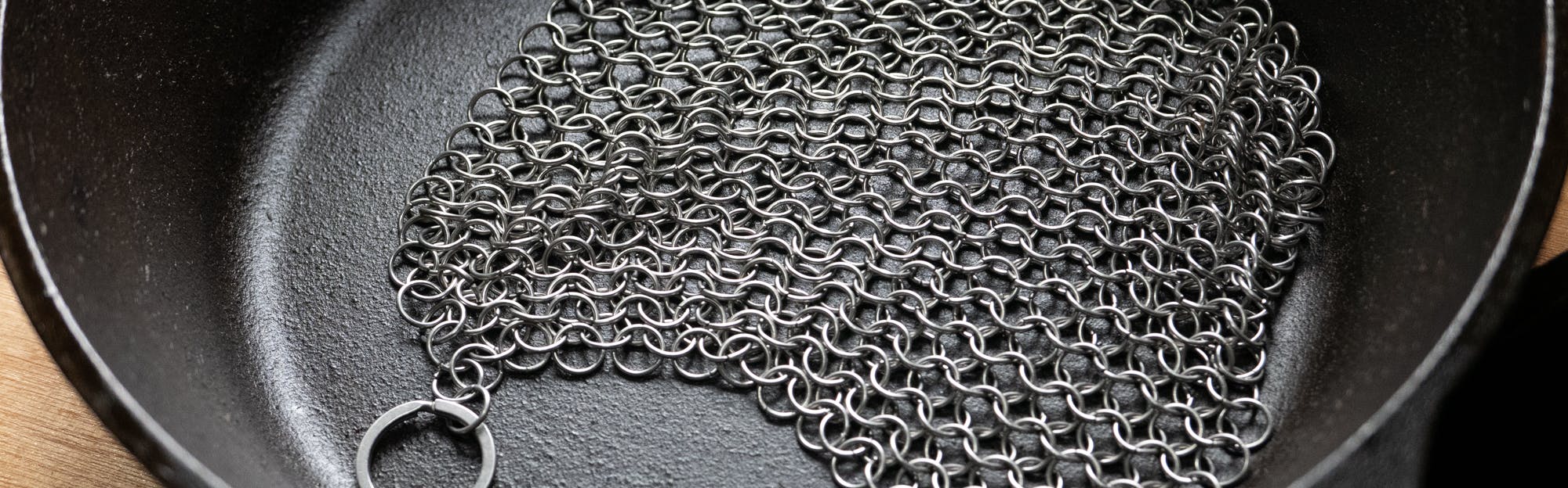 Stainless chainmail scrubber on a cast-iron pan. 