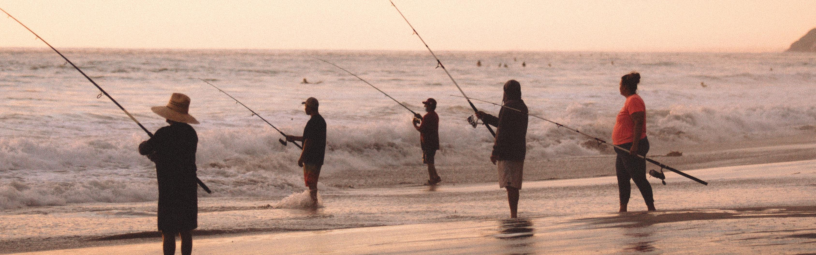 Five anglers stand in the waves and fish on the sea.