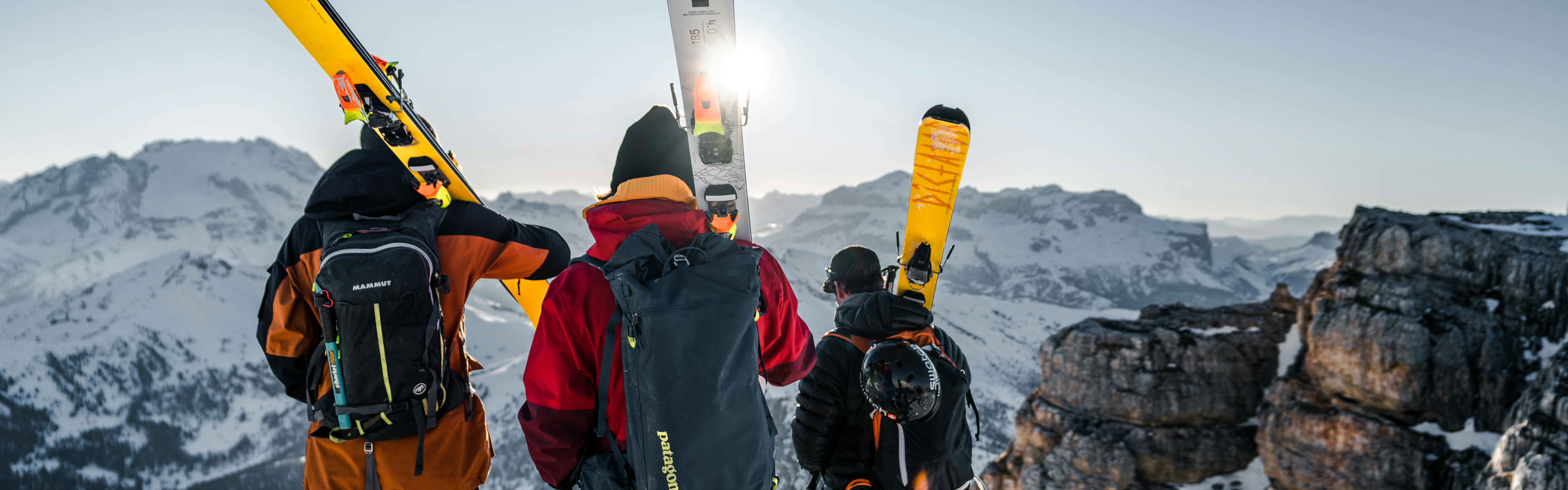 Three skiers carry their skis on their shoulders.