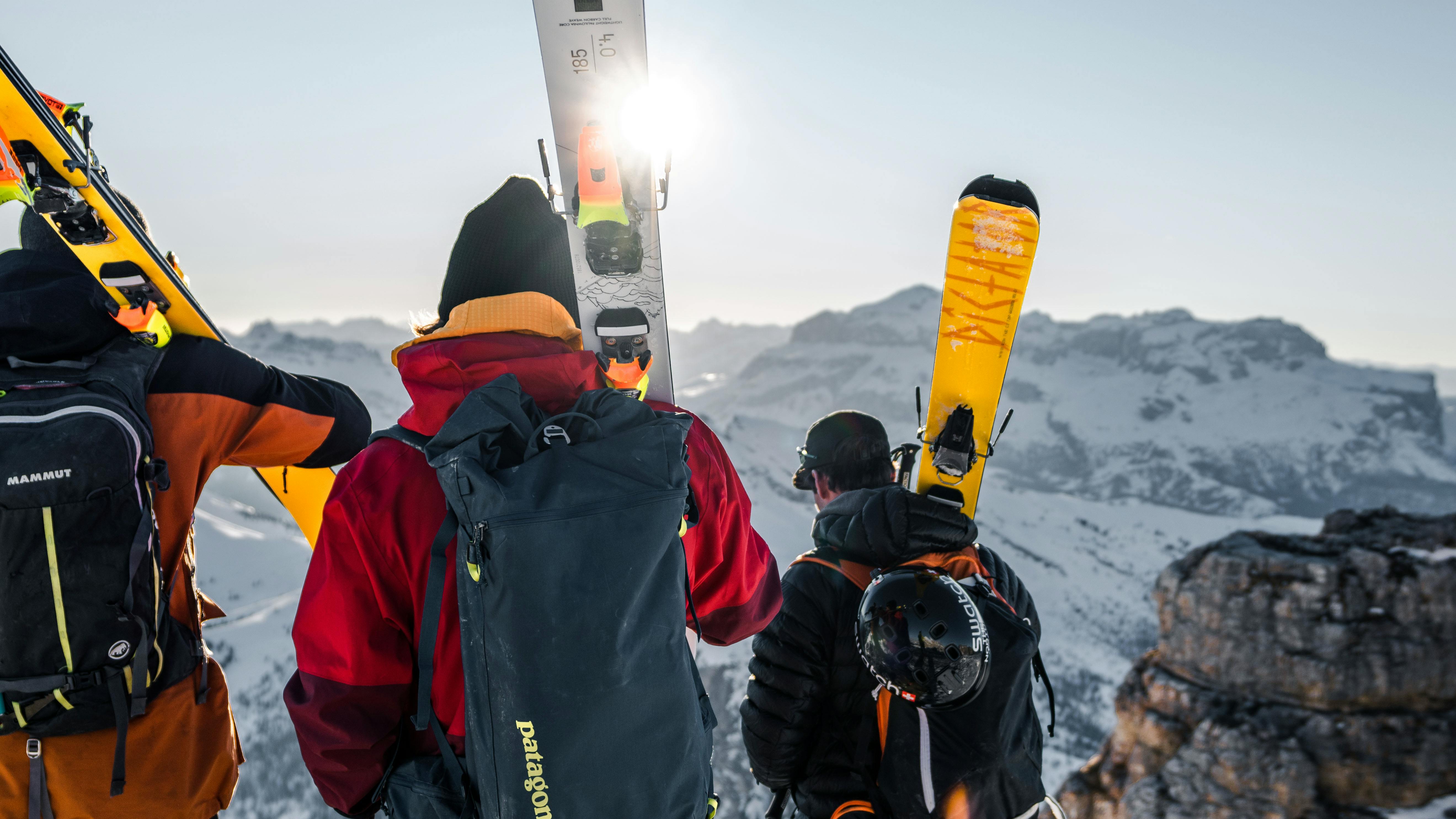 Three skiers carry their skis on their shoulders.