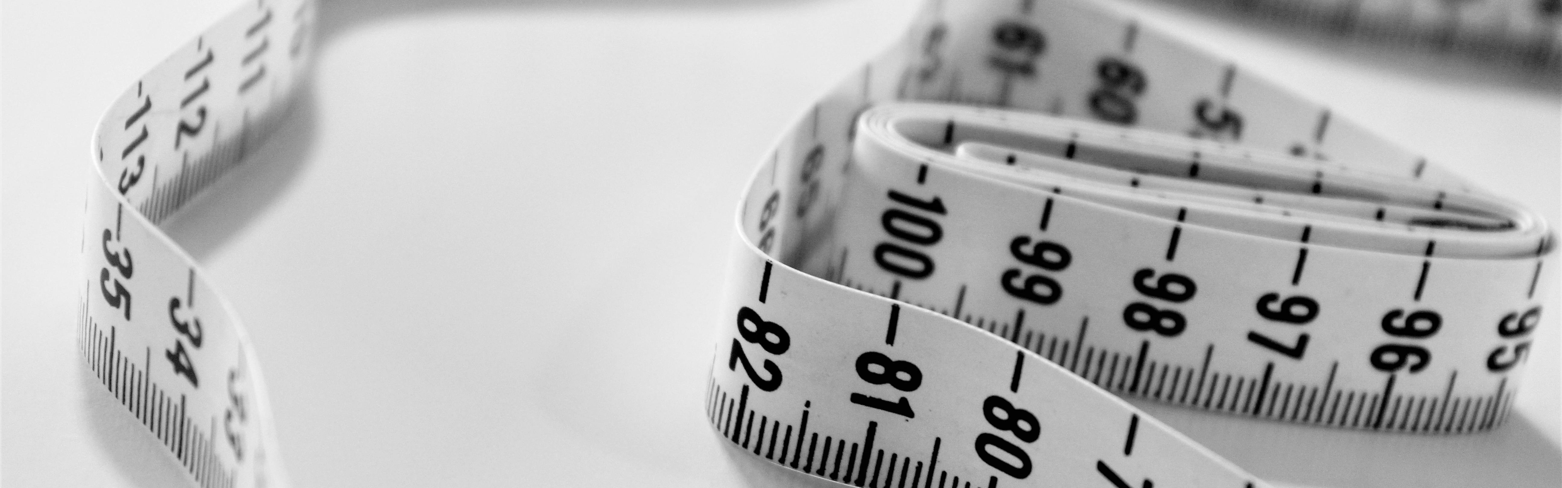 A roll of black and white measuring tape sitting on a white table.