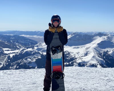 A snowboarder standing with the Salomon Huck Knife Snowboard. 