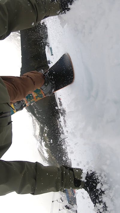 A snowboarder with his hand and snowboard on the snow. 