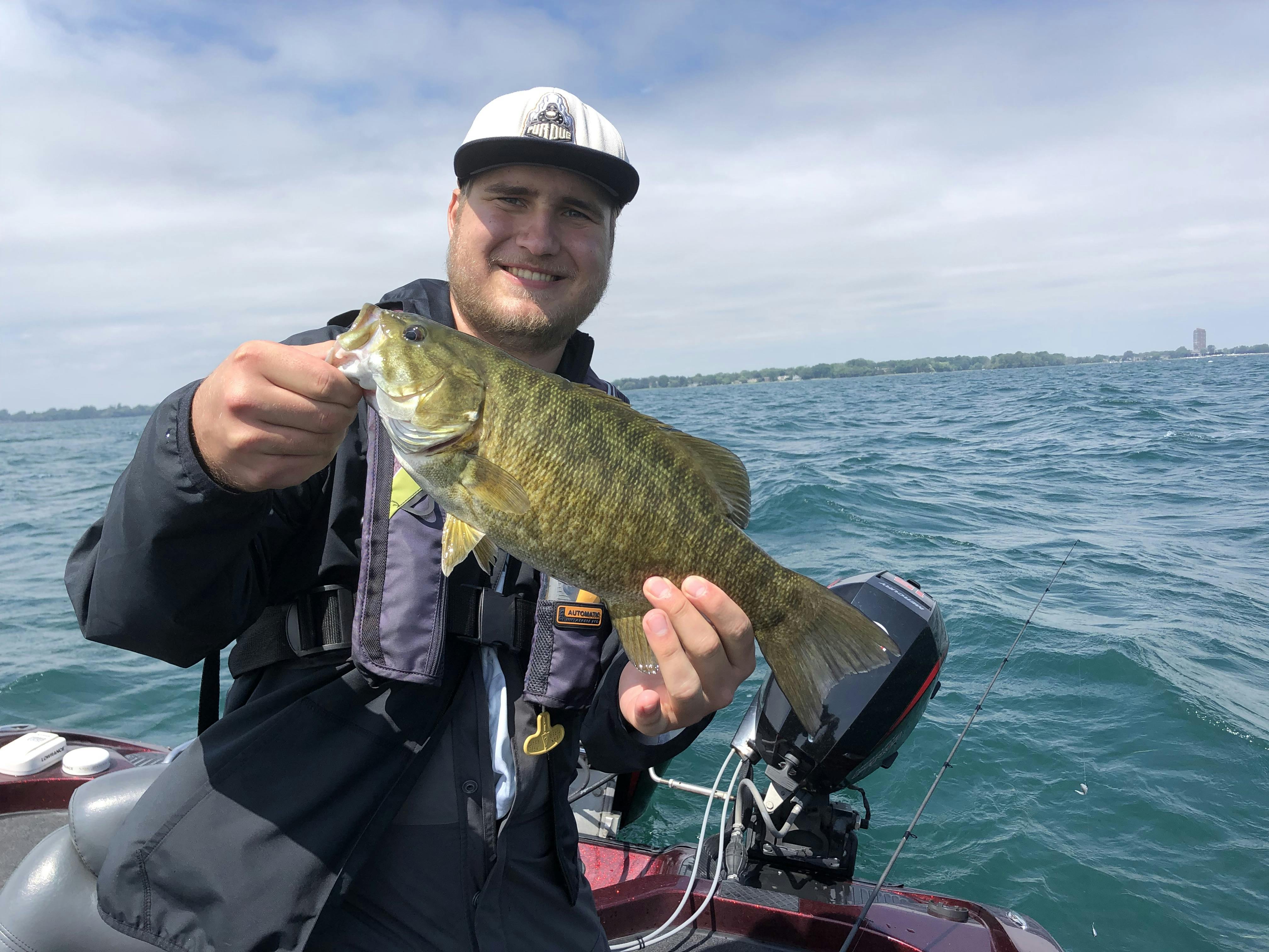 A man holds up a smallmouth bass caught on Lake St. Clair.