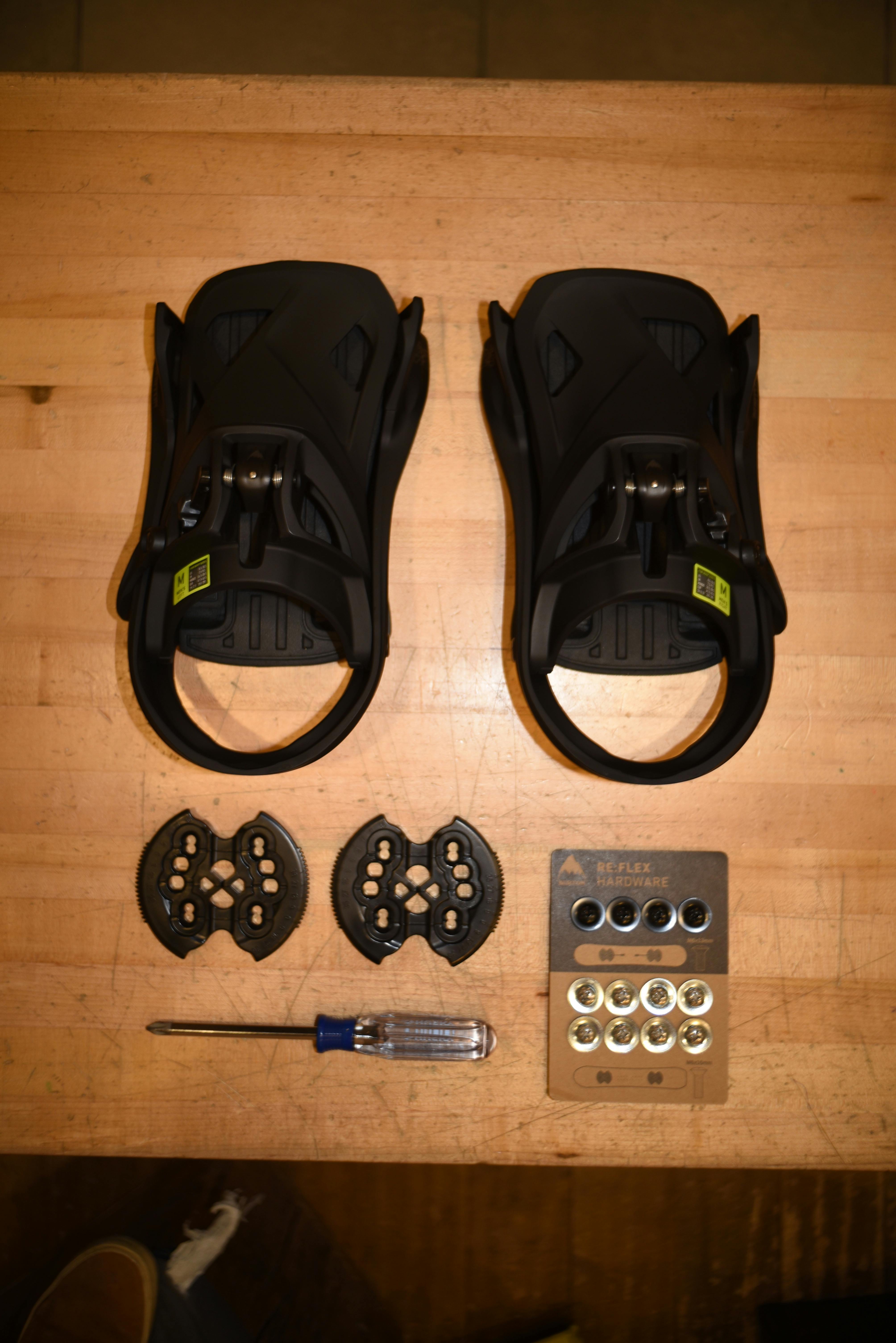 A pair of black snowboard bindings and the hardware required to mount them