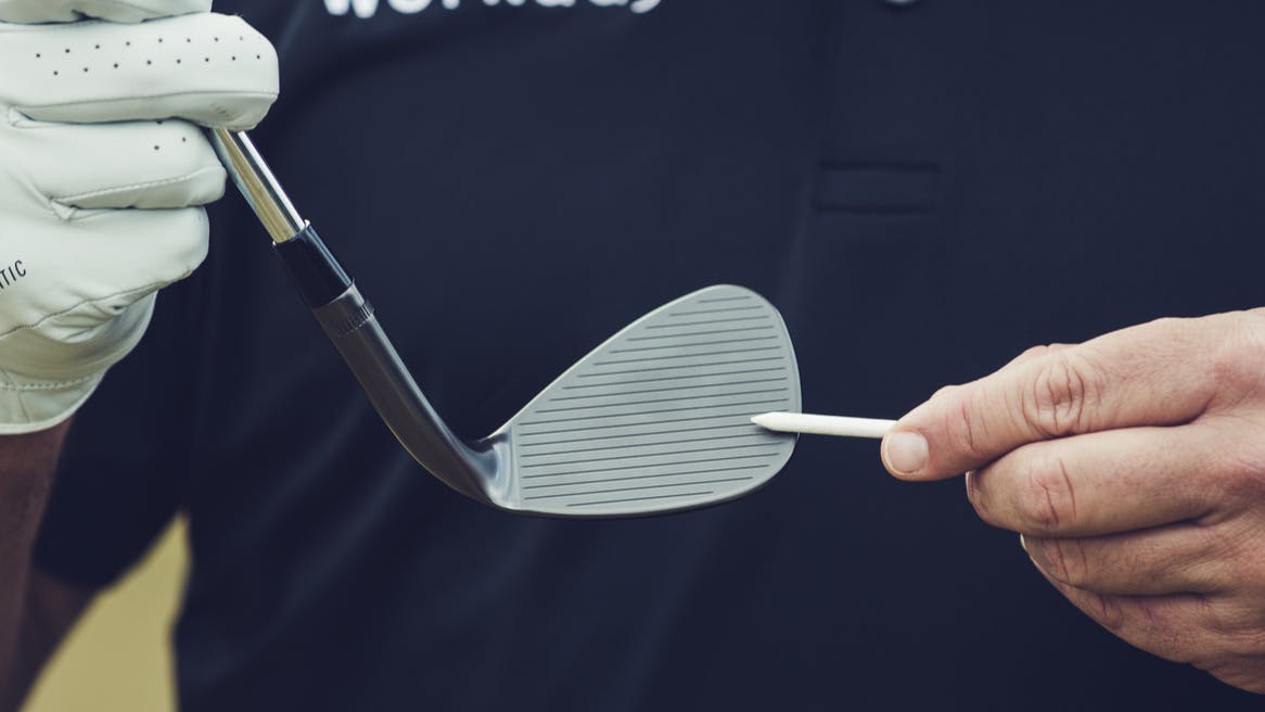 A man holds a wedge in his hand and points to the grooves.