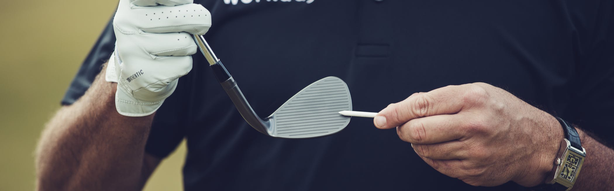 A man holds a wedge in his hand and points to the grooves.