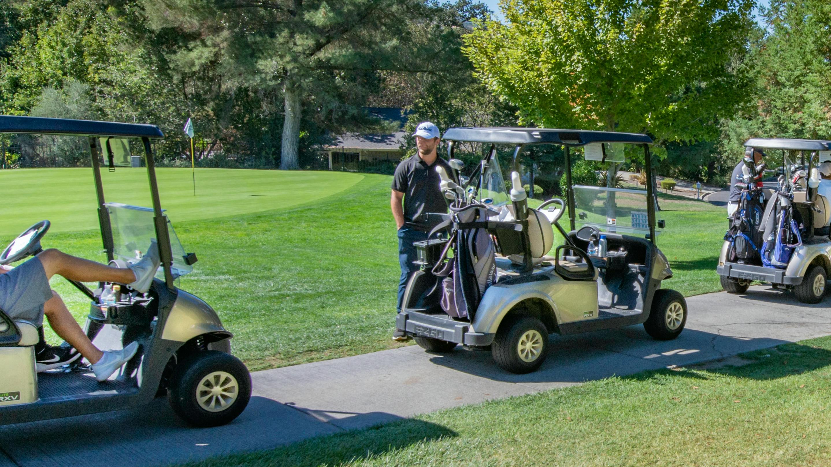 Four golf carts are lined up down a path. 