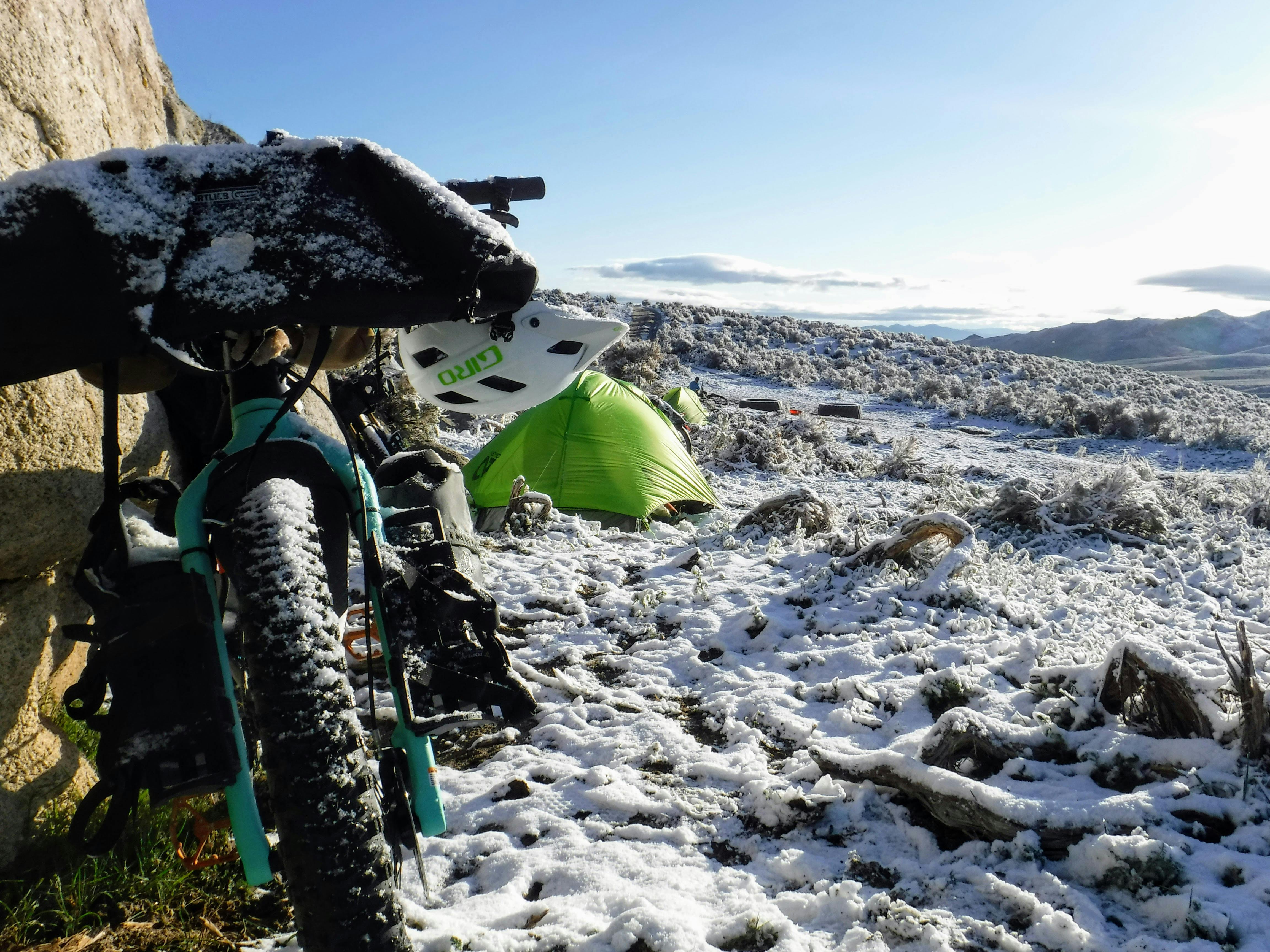 A tent and a bike both covered in snow. 