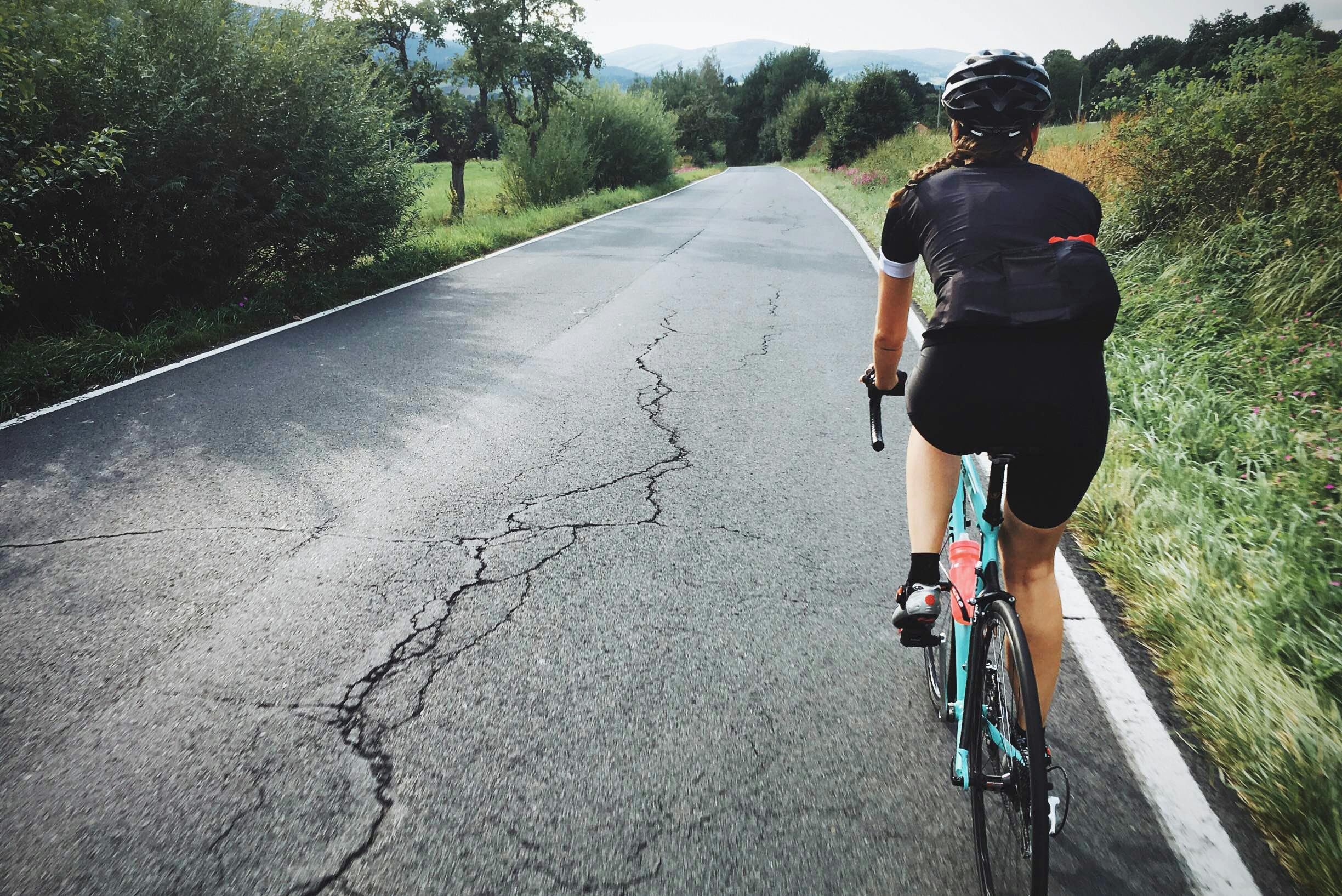 A woman on a road bike rides away from the camera