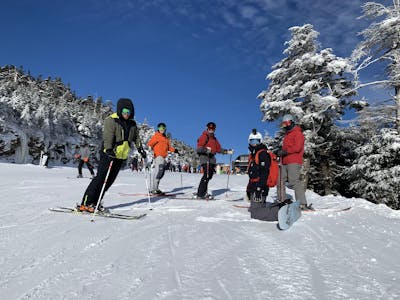Several skier and snowboarders on a ski run. 