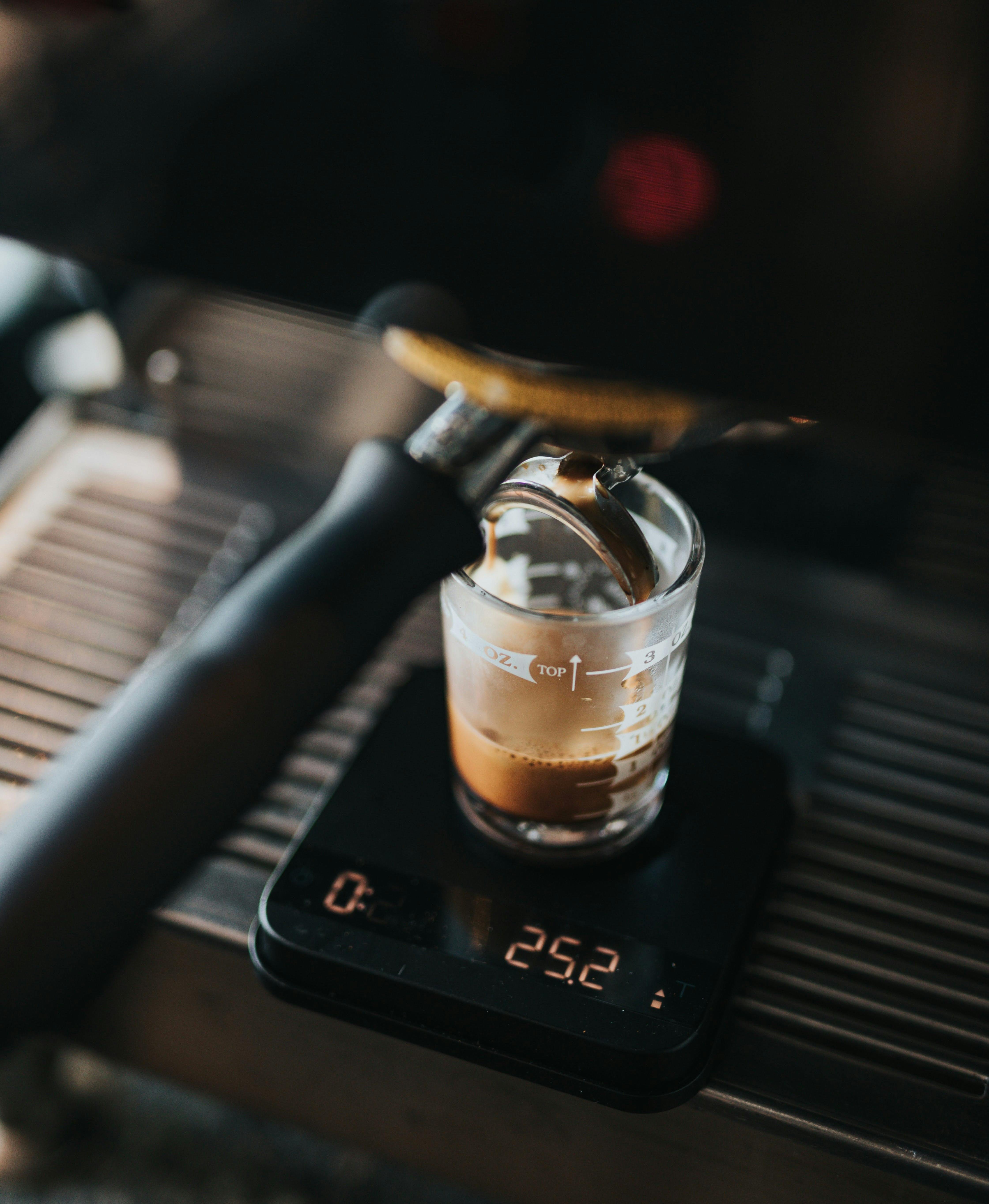 A double shot pours into a glass espresso shot glass on top of a digital scale. 