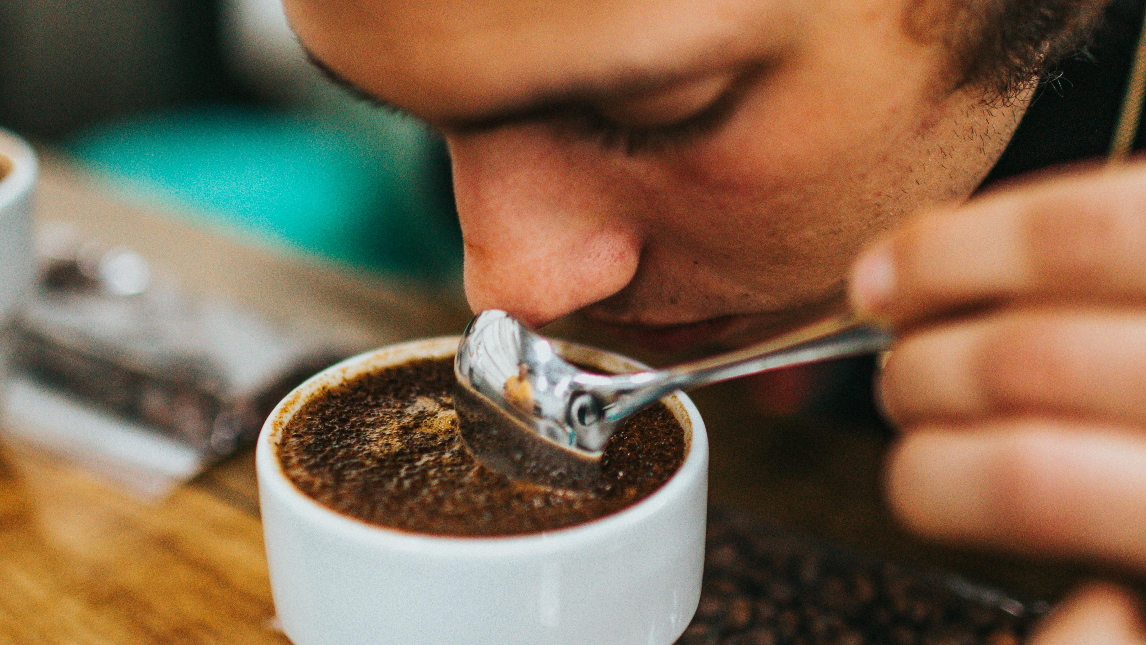 A man smelling a cup of espresso. 