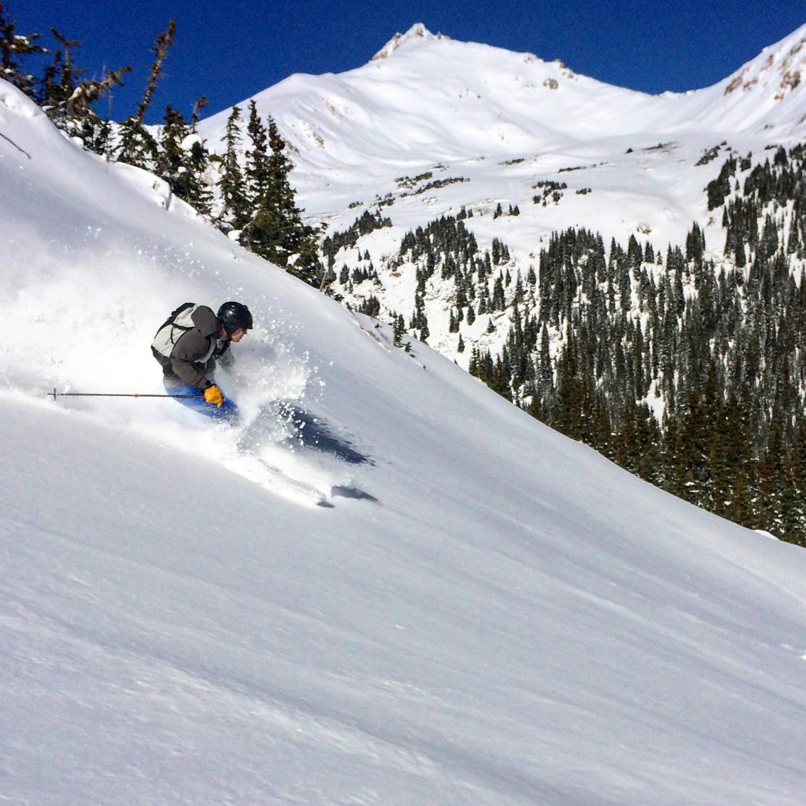 A skier riding down a steep slope in the backcountry