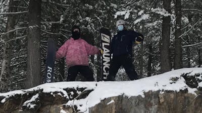 Two snowboarders at the top of a cliff.