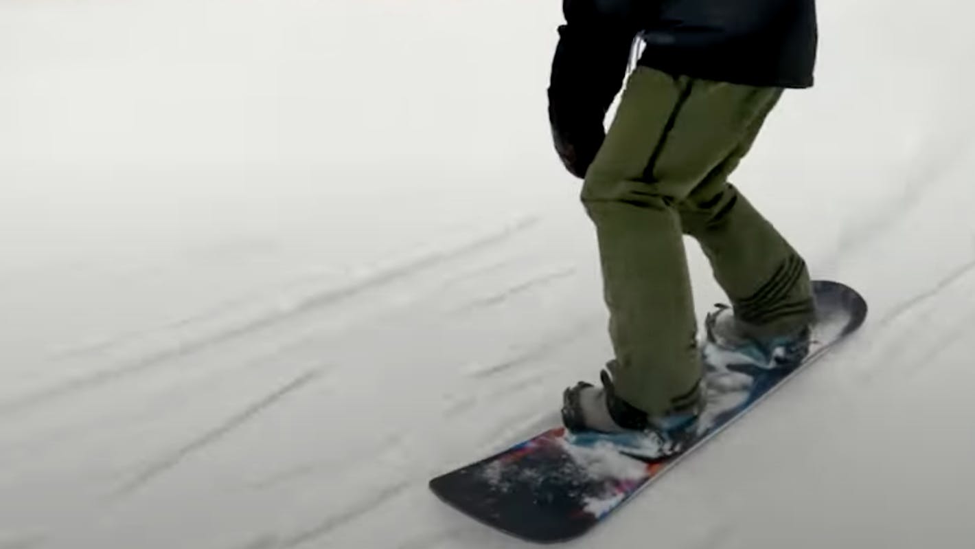 A snowboarder turning down a mountain. 