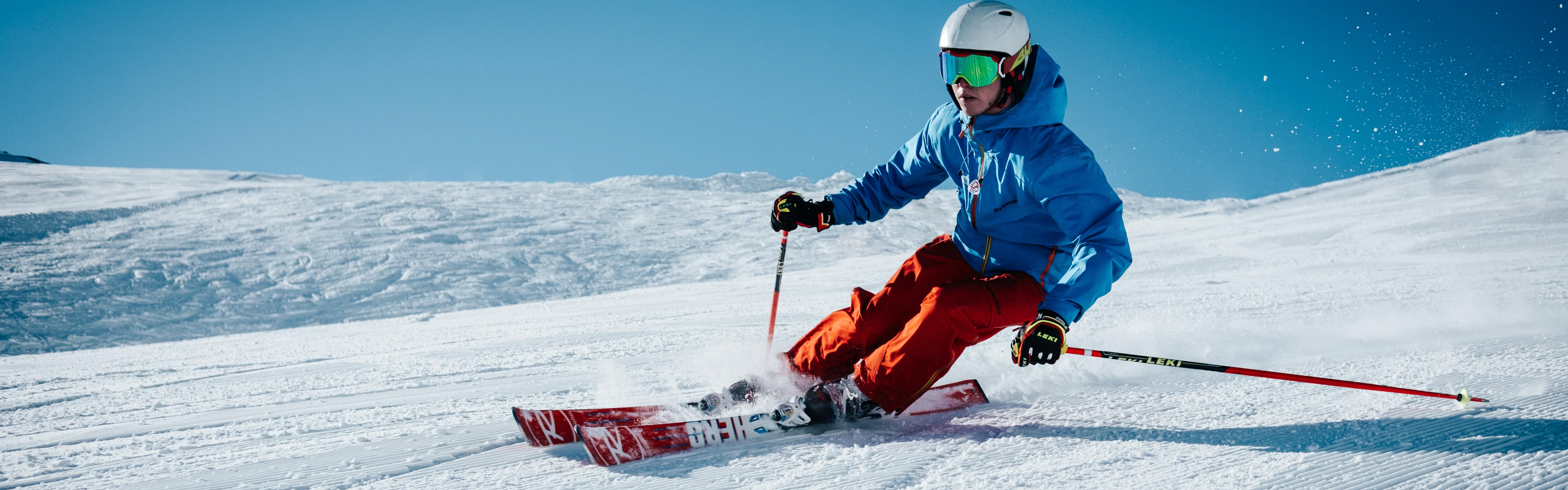 A skier turning down a ski trail. The tops of his skis and his ski bindings are visible as he turns. 