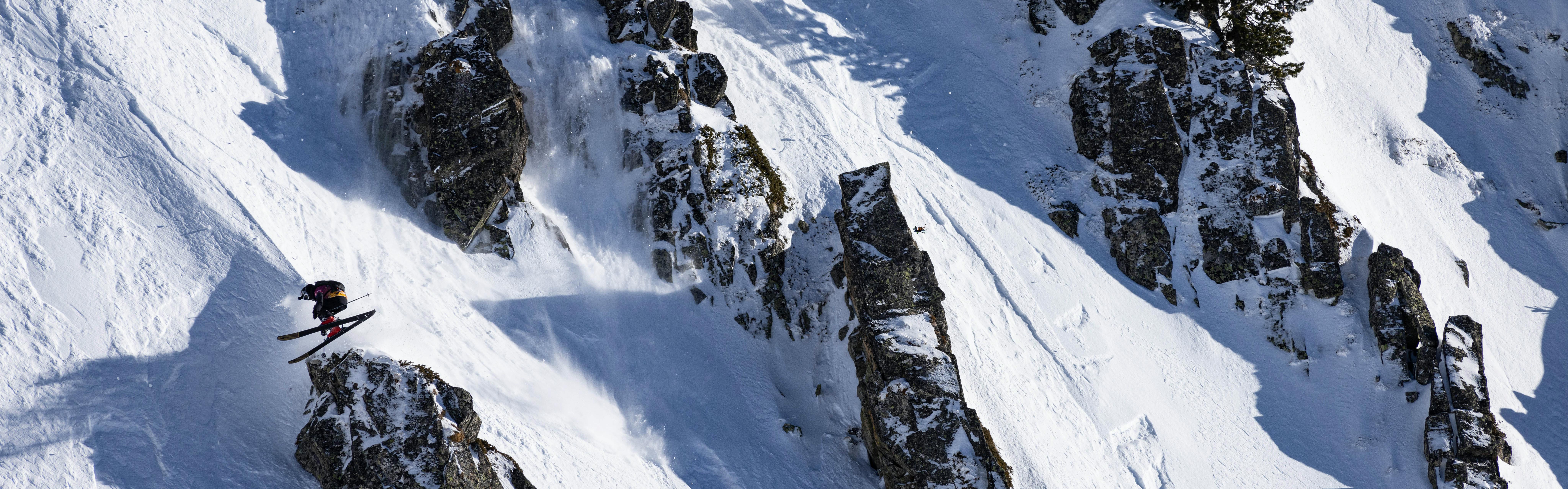 A skier jumps while on a near-vertical mountain.