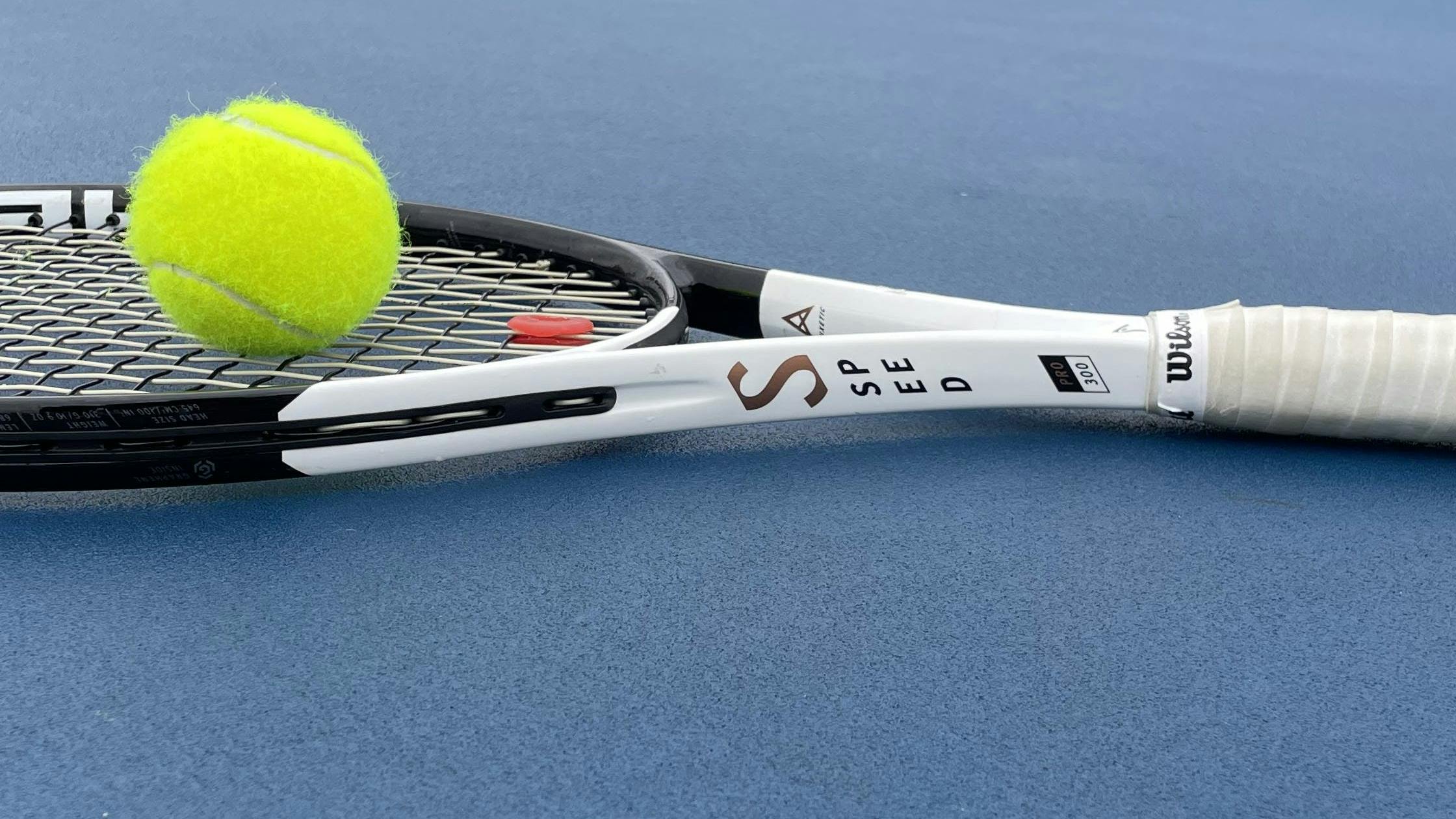 The Head Speed Pro 100 2022 Racquet  with a tennis ball on it. 
