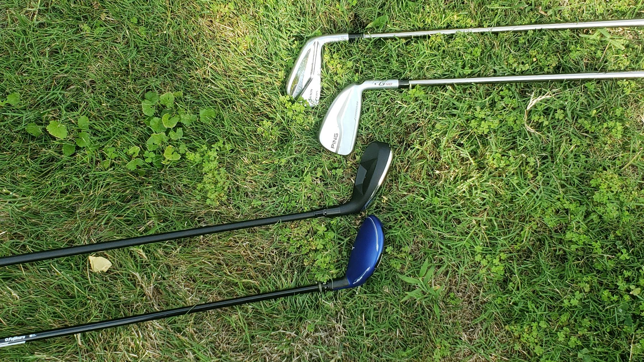 Four golf clubs lie on the grass