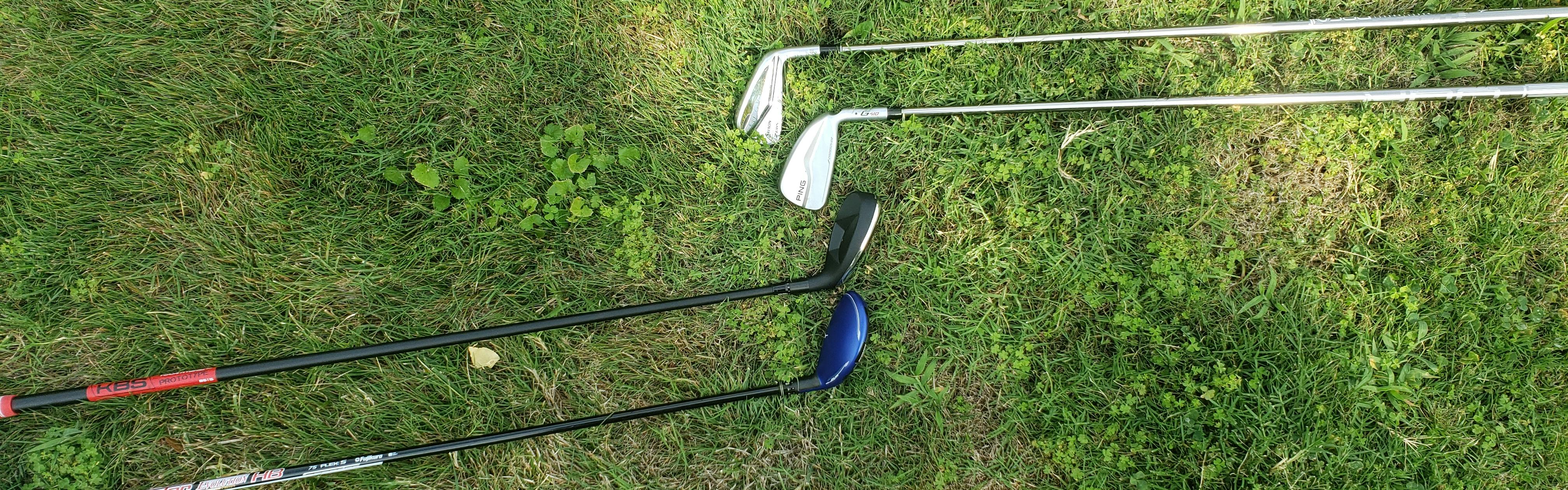 Four golf clubs lie on the grass