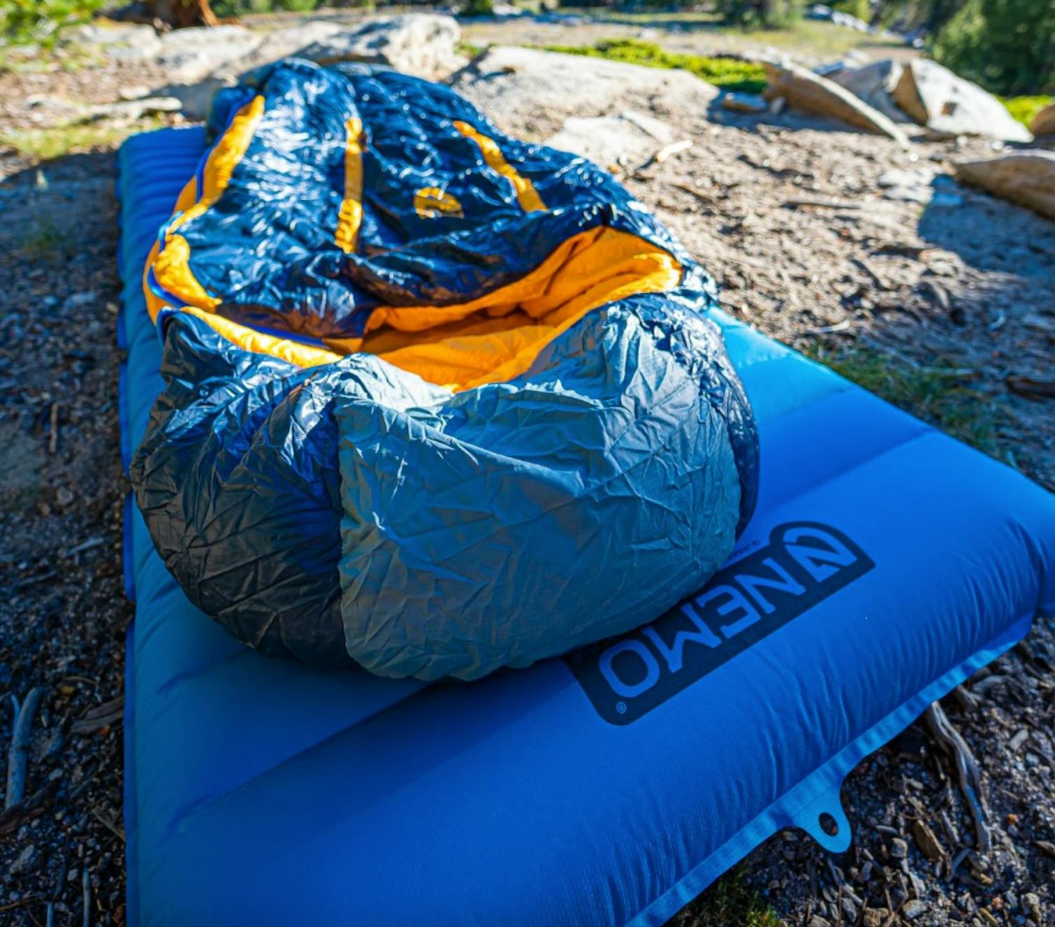 The Nemo Quasar Sleeping Pad lying on the ground with a sleeping bag on it. 