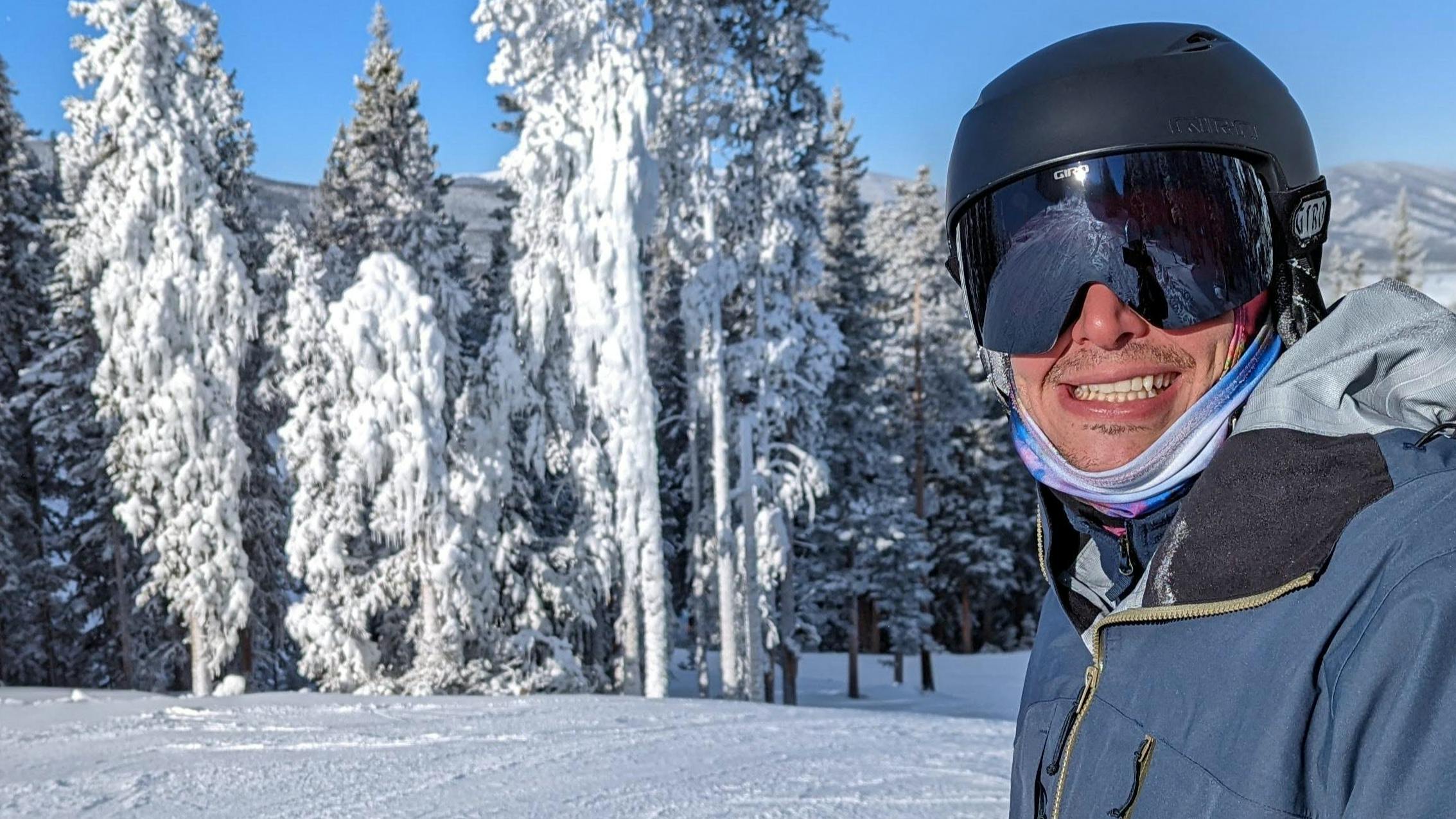 A skier smiling at the camera wearing the Giro Grid MIPS Helmet.