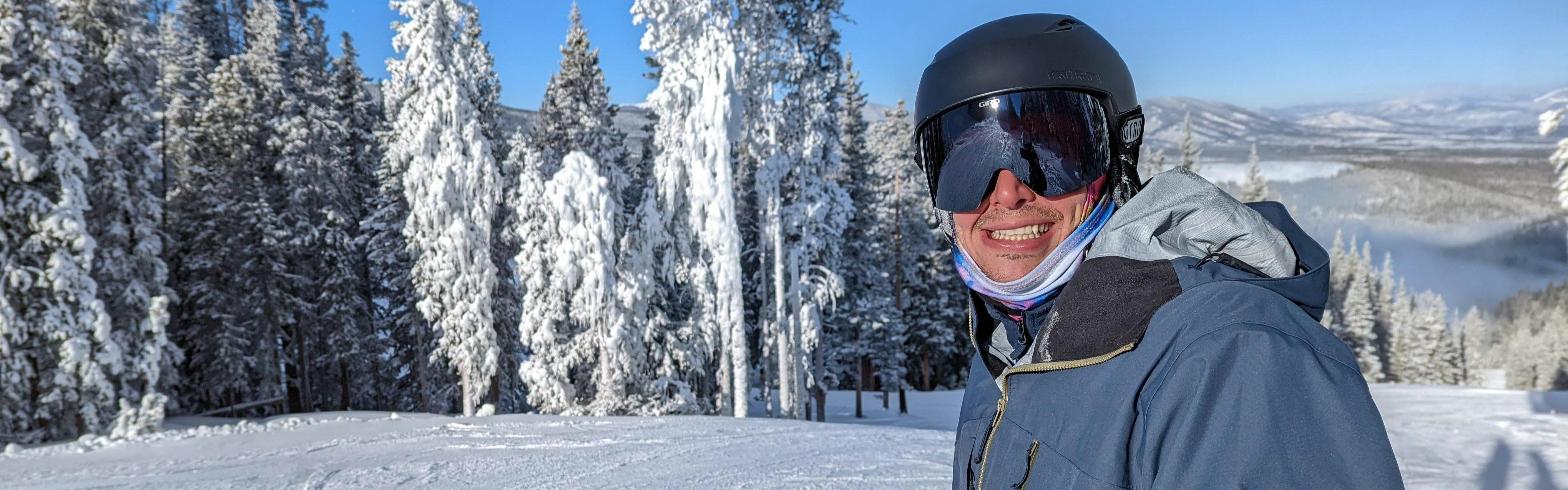 A skier smiling at the camera wearing the Giro Grid MIPS Helmet.