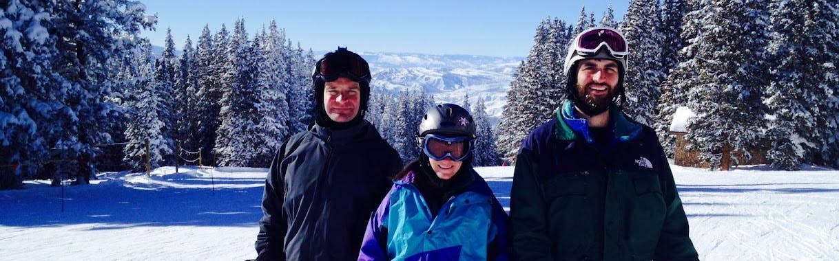 Three people in ski gear stand on a ski run. 