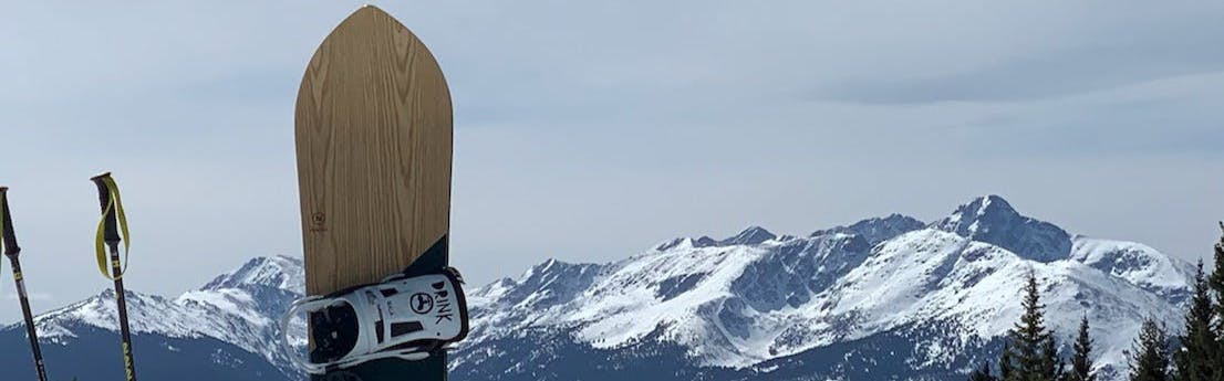 The Nidecker Mellow Snowboard · 2022 with a snowy mountain range in the background. 