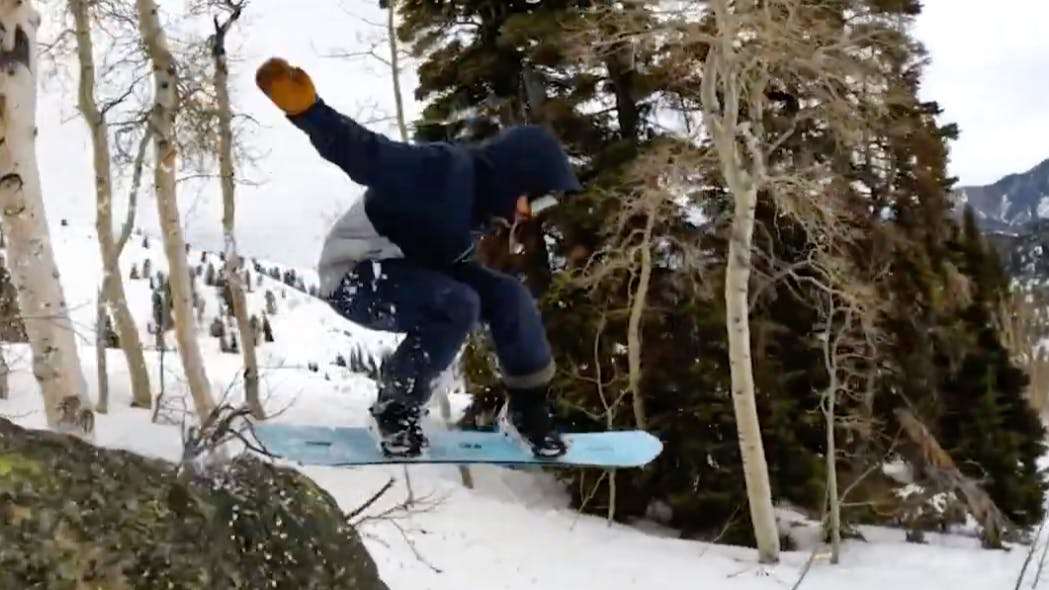 Snowboard Expert Matthew Kaminski jumping off a boulder with the 2023 K2 Passport snowboard
