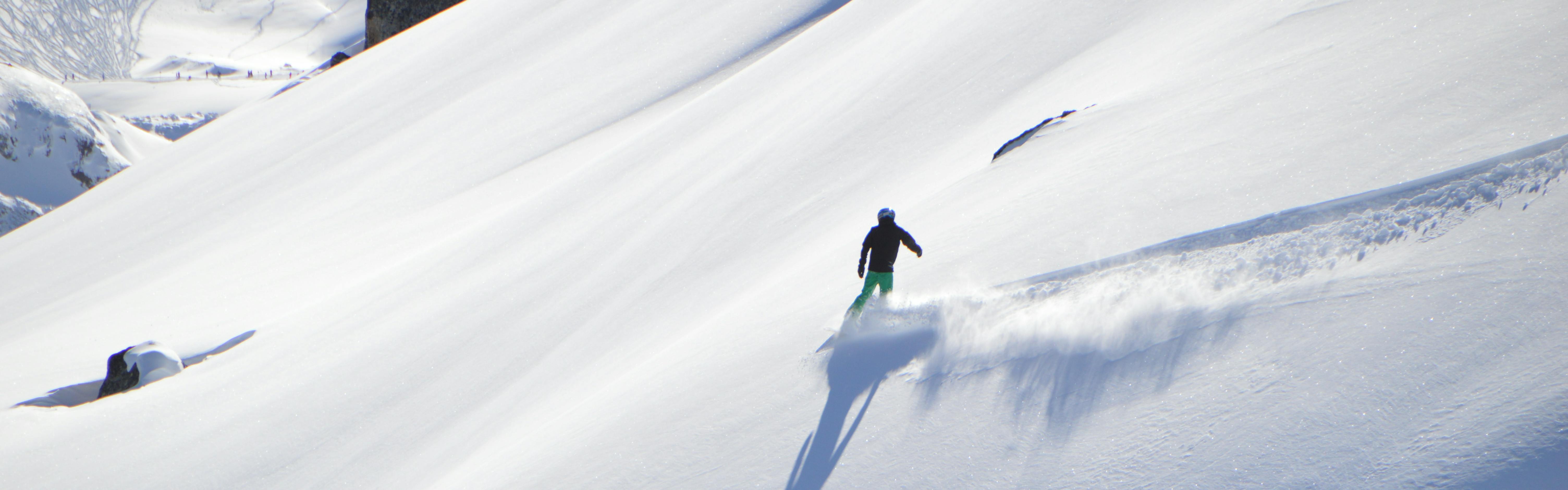 A snowboarder rides across a powdery mountain. 
