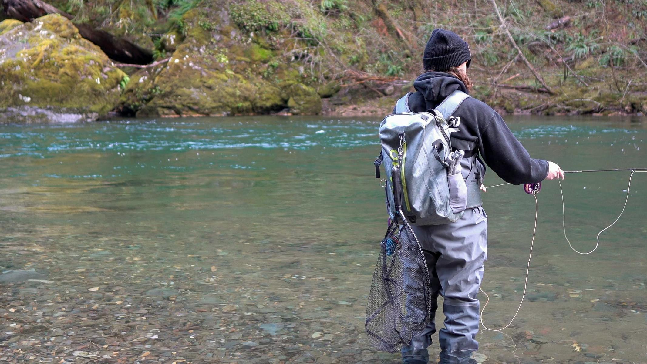 A fisherman stands in a river casting a fly line and wearing the Orvis Men's PRO Waders.