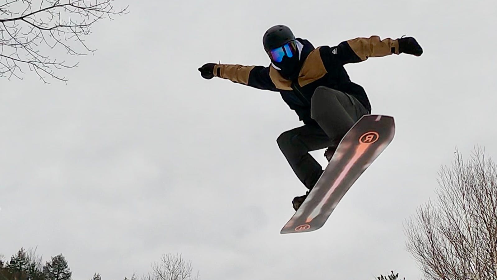 Looking up at a snowboarder flying through the air